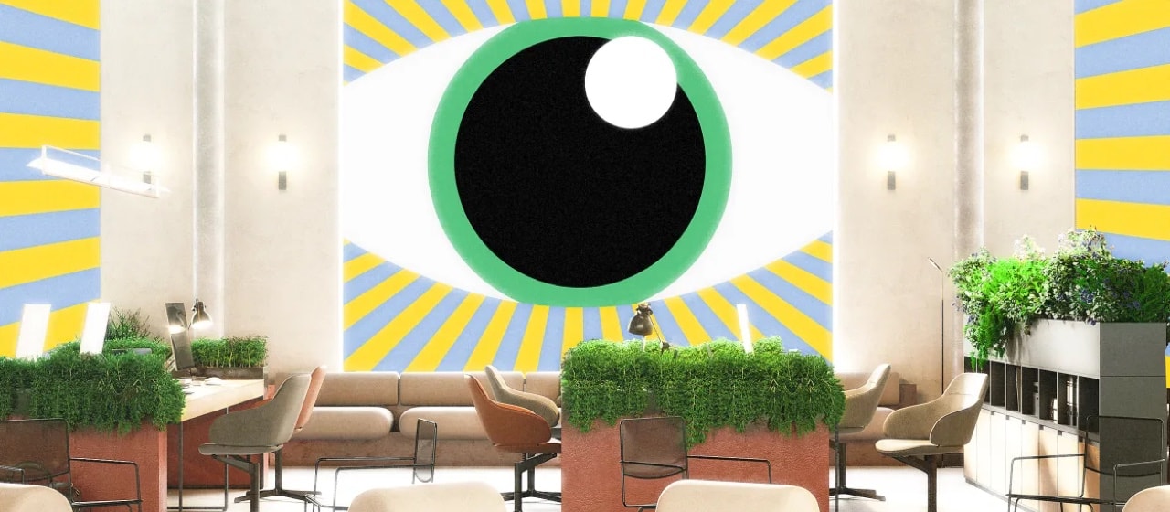 A photograph of a bright office space with lots of plants no brown desks with brown chairs. In the background there's a large illustration of an eye with a green iris, and there are yellow and blue lines emanating from it.
